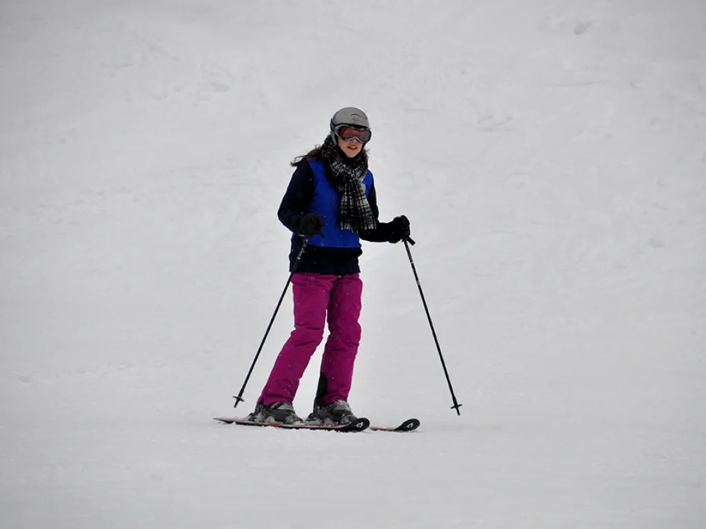 Skifahrerin in pinker Hose auf der Piste.